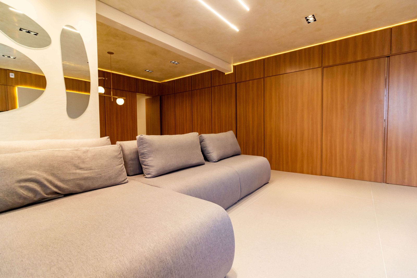 Home theater planejado com painel de madeira ripado, iluminação embutida e sofá confortável, compondo um espaço elegante para entretenimento.